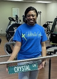 Crystal Lane poses with the Crystal Ln street sign on the parallel bars