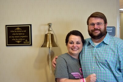 Connie Kelly hugs her husband with tears in her eyes after ringing a bell signifying the end of her chemotherapy treatments. 