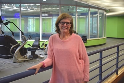 Eileen Bailey in a pink sweater smiling after a walk on the NMMC Wellness Center track. 