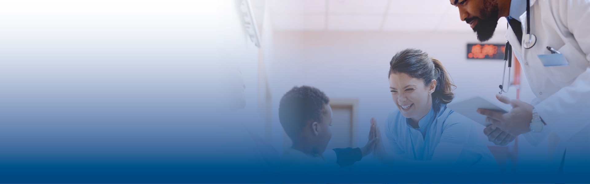 a young boy high fives a doctor while another doctor looks on