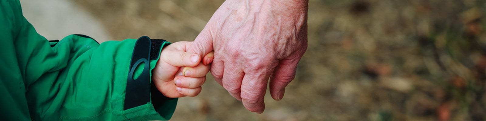 a young child holds a finger on an older person's hand