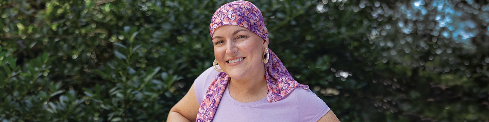 Ashleigh Pharr poses outside wearing a pink and purple paisley head scarf