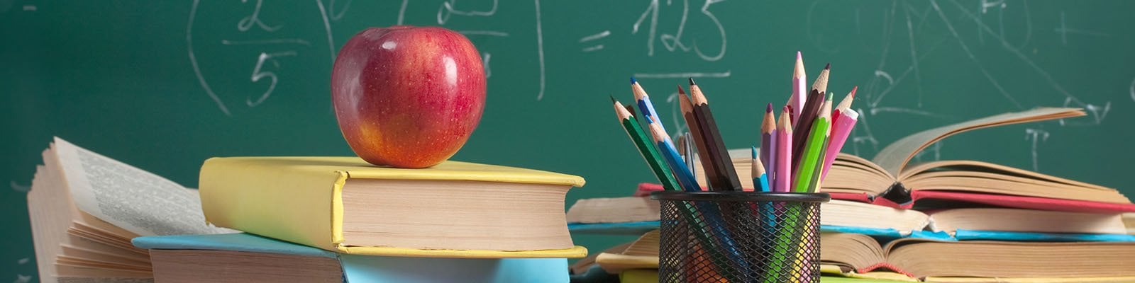 books and school supplies in front of a chalkboard