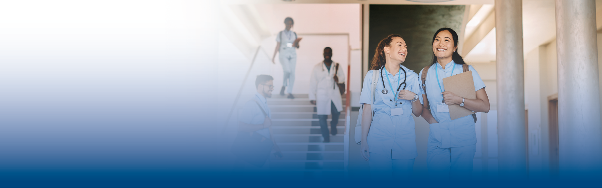 two student nurses walking and talking together and other students coming down the stairs behind them