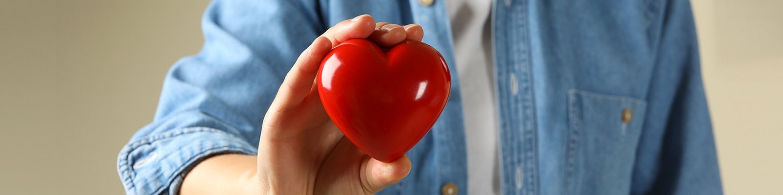 woman in jean shirt holding red heart