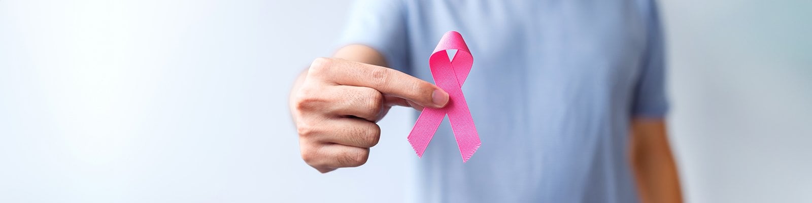 a man holds a pink breast cancer awareness ribbon