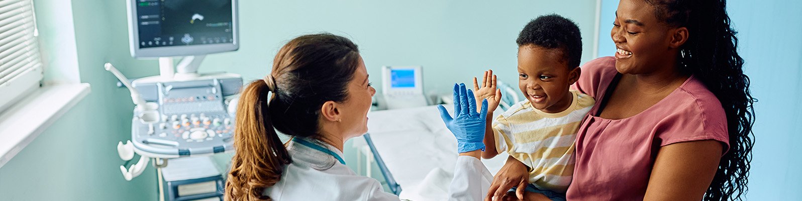 young child on his mother's lap high-fives with a doctor