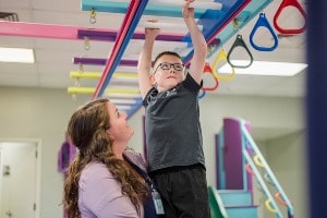 therapist working with child on monkey bars