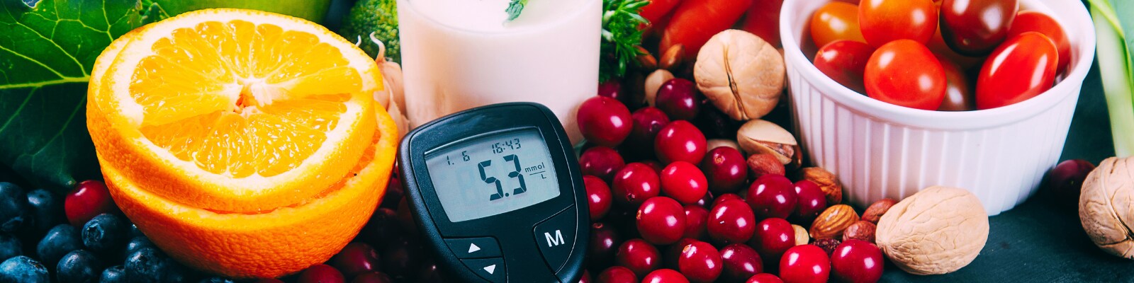 diabetes monitor next to a spread of fruits, vegetables and nuts